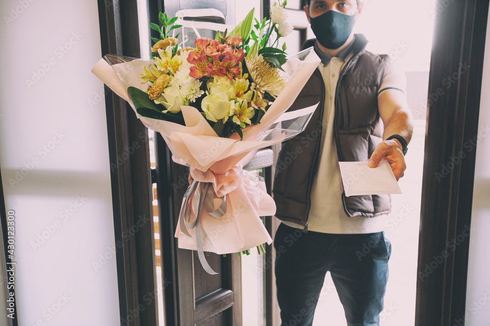 The delivery man delivers a bouquet of beautiful flowers to home - obrazy, fototapety, plakaty 