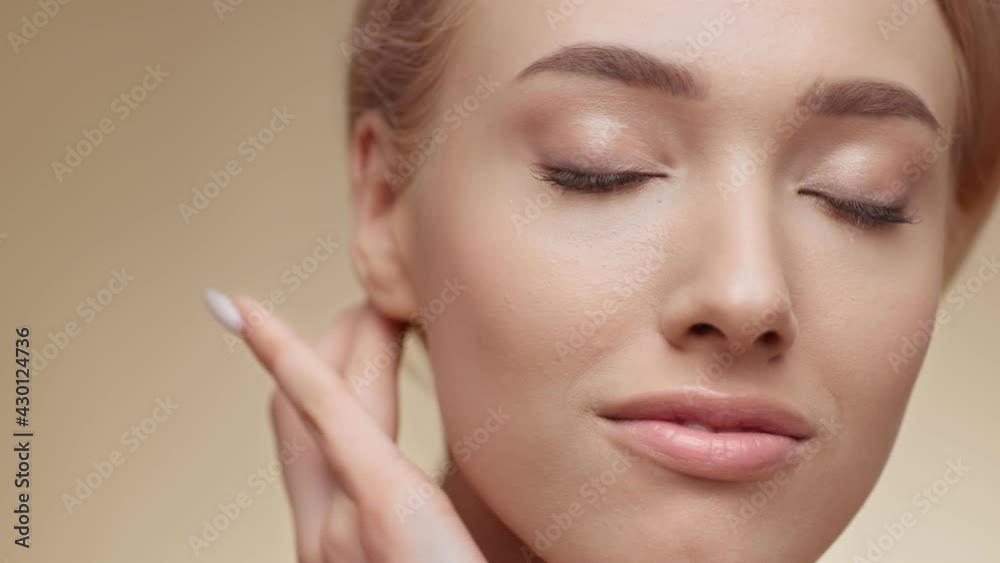 Female beauty. Beautiful young blonde lady touching her face and smiling to camera, beige studio background, empty space Female beauty. Beautiful young blonde lady touching her face and smiling to camera, beige studio background, empty space