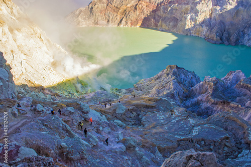 Beautiful sulfuric acid lake and gas coming out of the sulphur mines in the crater on the bottom of Mount Kawah Ijen active volcano, Banyuwangi, East Java, Indonesia. 