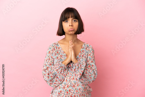 Young pregnant woman over isolated pink background keeps palm together. Person asks for something © luismolinero