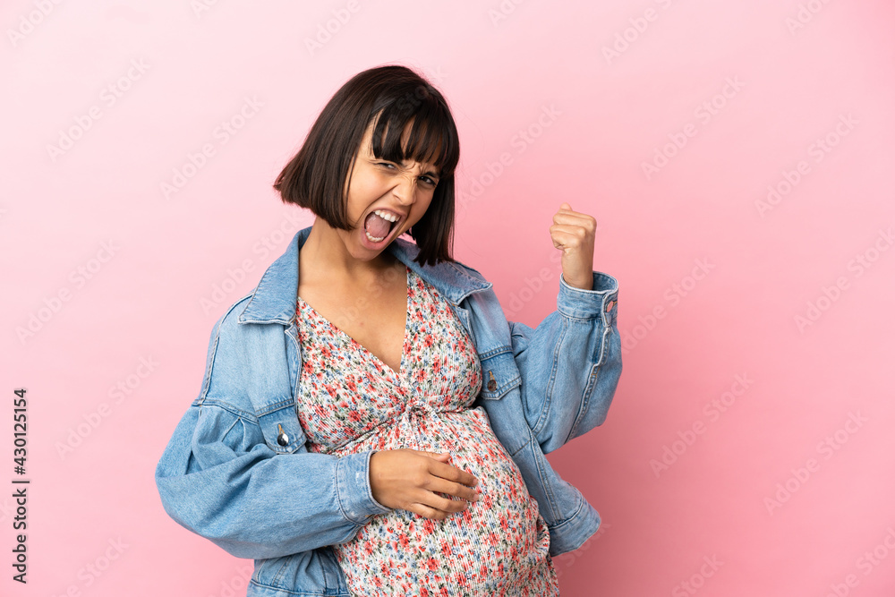 Obraz premium Young pregnant woman over isolated pink background celebrating a victory