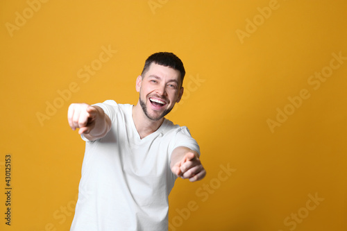 Handsome man laughing on yellow background, space for text. Funny joke