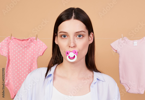Portrait, a young mother posing with a pacifier in her mouth.