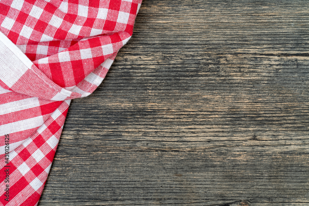 Obraz premium Red checkered towel on the kitchen table. Wooden table background.