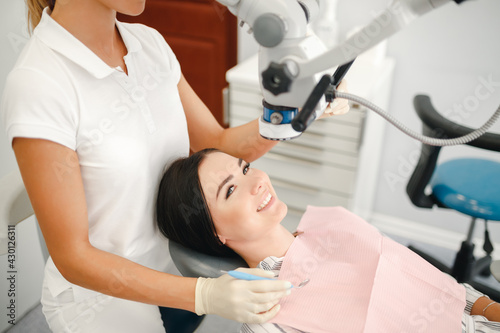 A dentist is looking in a special microscope for dentist in a laboratory wit patient sit in the chair. Close-up of female dentistry at the workplace