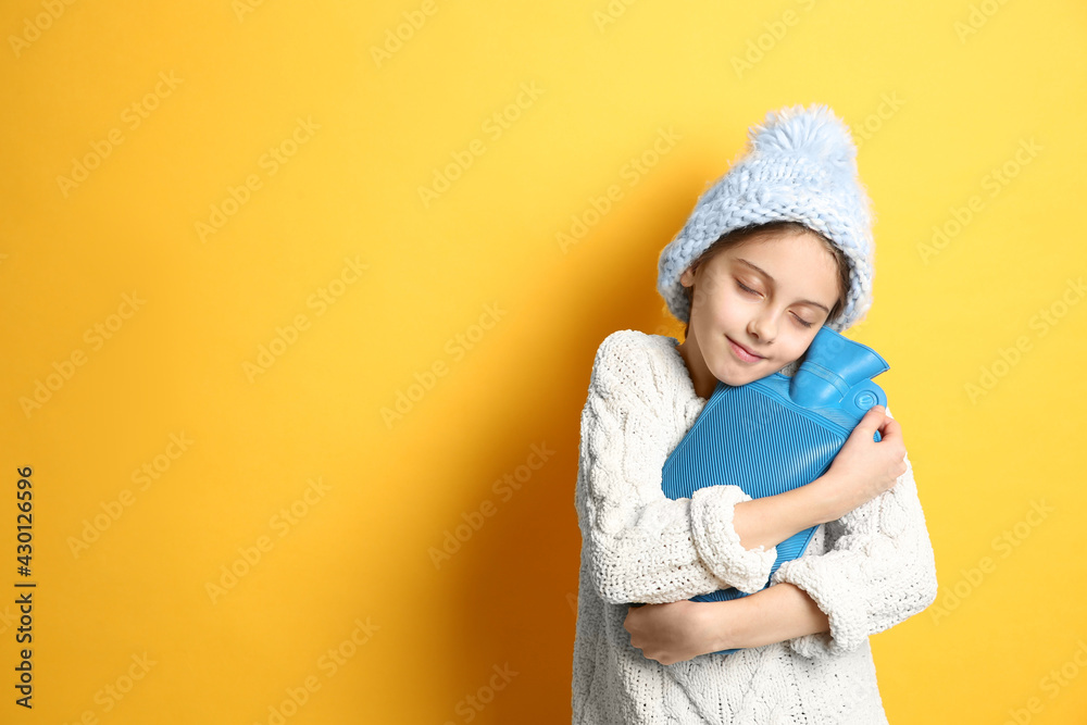Ill girl with hot water bottle suffering from cold on yellow background, space for text