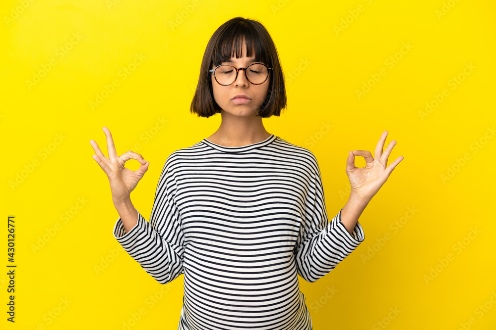 Young pregnant woman over isolated yellow background in zen pose