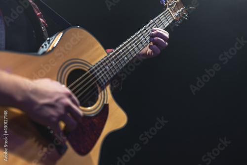 Guitarist playing acoustic guitar in the dark.
