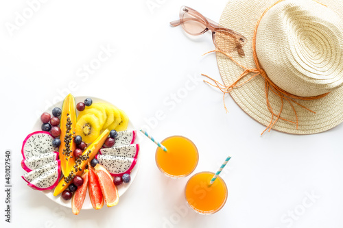 Exotic fruit salad in white plate. Fruits with fresh juice and hat, top view