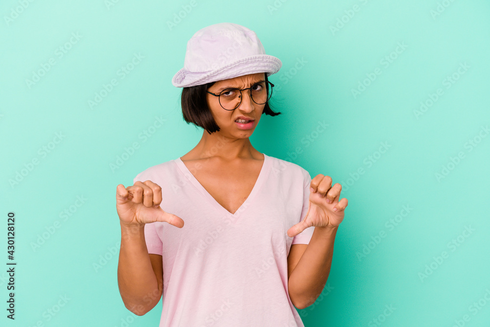 Young mixed race woman isolated on blue background showing thumb down and expressing dislike. Young mixed race woman isolated on blue background showing thumb down and expressing dislike.