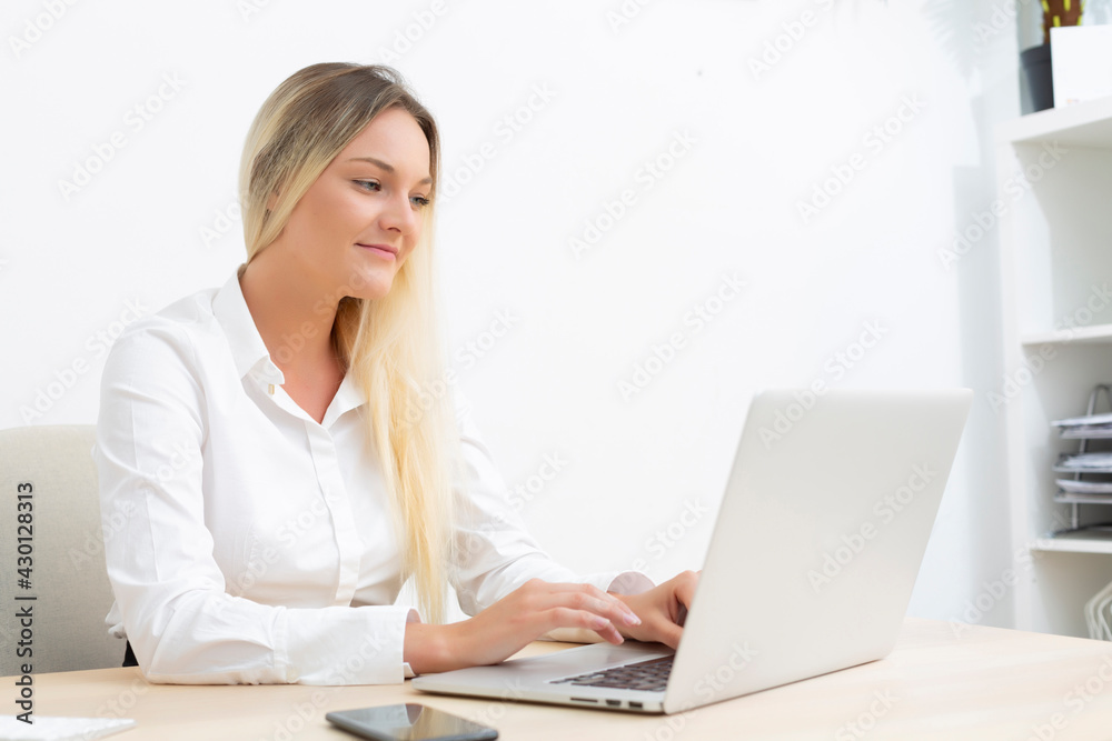 Attractive young Caucasian businesswoman smiling working in front of computer in office. Attractive young Caucasian businesswoman smiling working in front of computer in office.