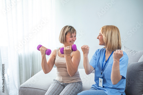Shot of a mature woman using weights with the help of a physical therapist. Personal trainer helping mature woman exercise at home. Woman working through her recovery with a female physiotherapist