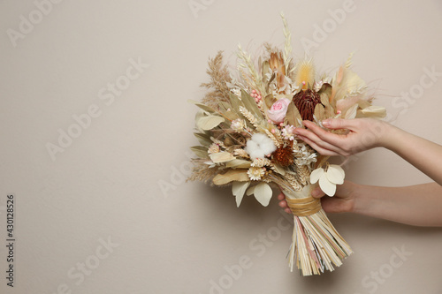 Woman holding beautiful dried flower bouquet on beige background, closeup. Space for text