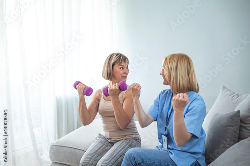 A Modern rehabilitation physiotherapy worker with woman client. Beautiful cheerful professional nurse doing some physiotherapy exercises with mature patient.