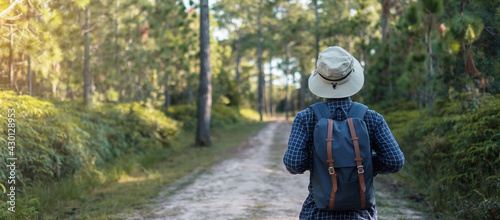 Foto Young man with backpack and hat hiking in mountains during summer season, solo traveler walking in the forest