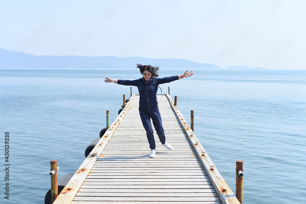 45 y.o. Russian woman running on a wooden pier by the Japanese sea