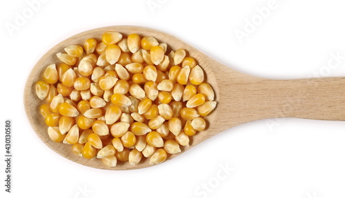 Corn grains, kernels in wooden spoon isolated on white background, top view