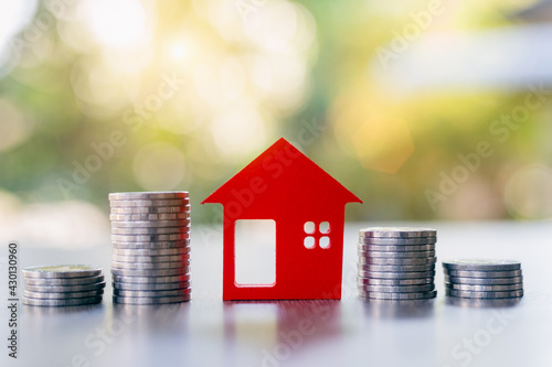 Red houses and a pile of coins. Home based loan ideas. Money from business finance coins. Successful financial business. Savings for real estate projects, mortgages, rentals.