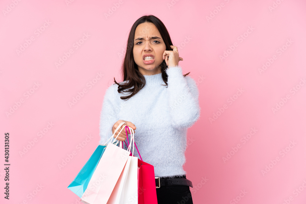 Young woman with shopping bag over isolated pink background frustrated and covering ears Young woman with shopping bag over isolated pink background frustrated and covering ears