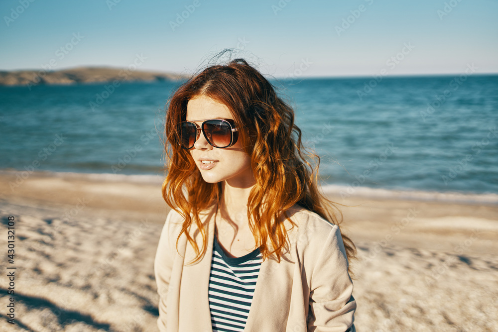 woman with glasses red hair model beige jacket sand beach sea