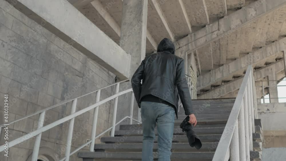 A private detective or spy with a camera climbs the steps of an abandoned stadium. A private detective or spy with a camera climbs the steps of an abandoned stadium.
