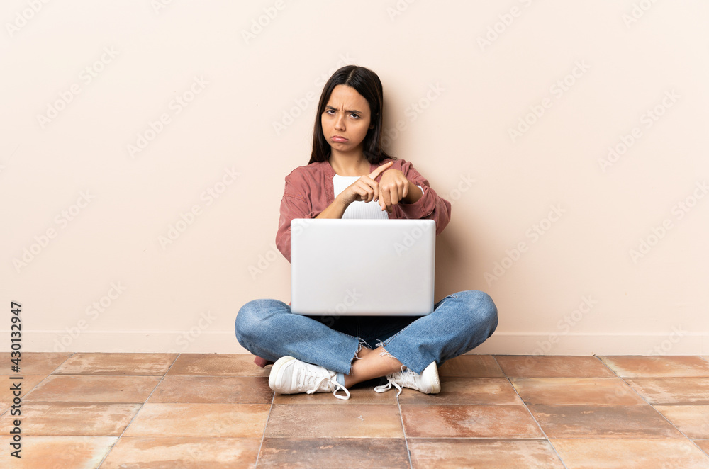 Young mixed race woman with a laptop sitting on the floor making the gesture of being late Young mixed race woman with a laptop sitting on the floor making the gesture of being late