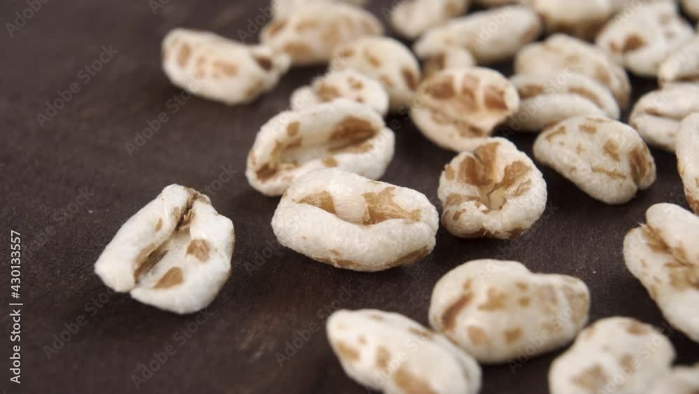 Puffed spelt wheat on a dark wooden background. Uncooked cereal. Macro. Dolly shot Puffed spelt wheat on a dark wooden background. Uncooked cereal. Macro. Dolly shot