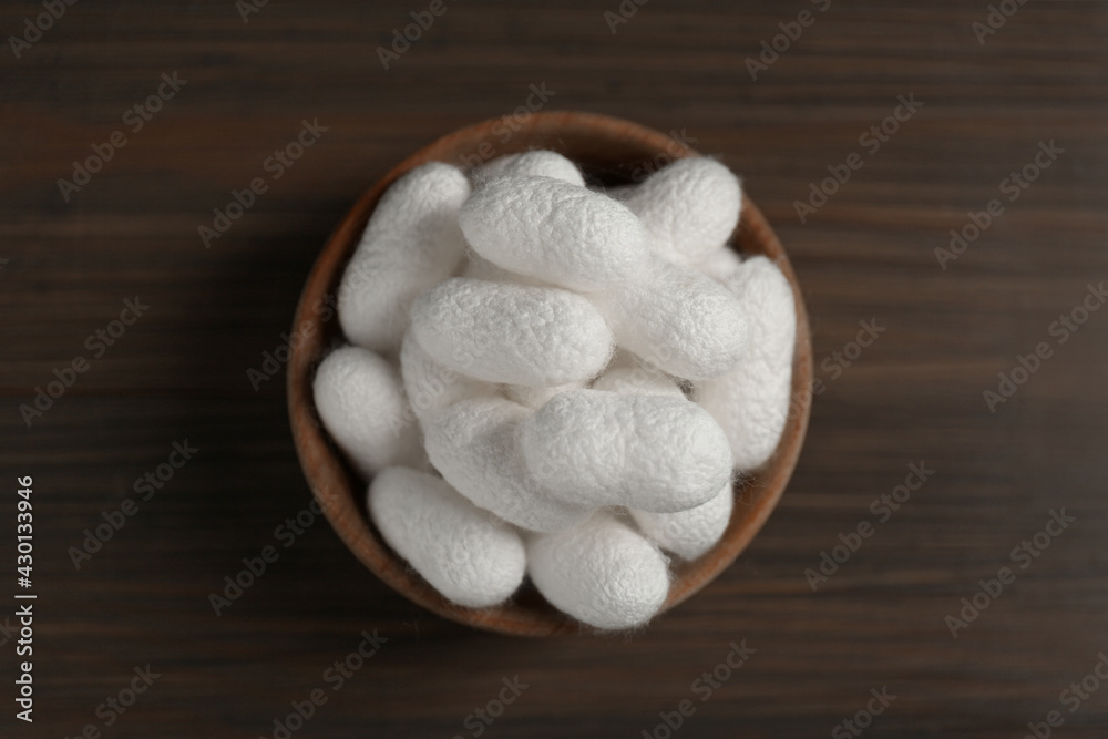 White silk cocoons in bowl on wooden table, top view White silk cocoons in bowl on wooden table, top view