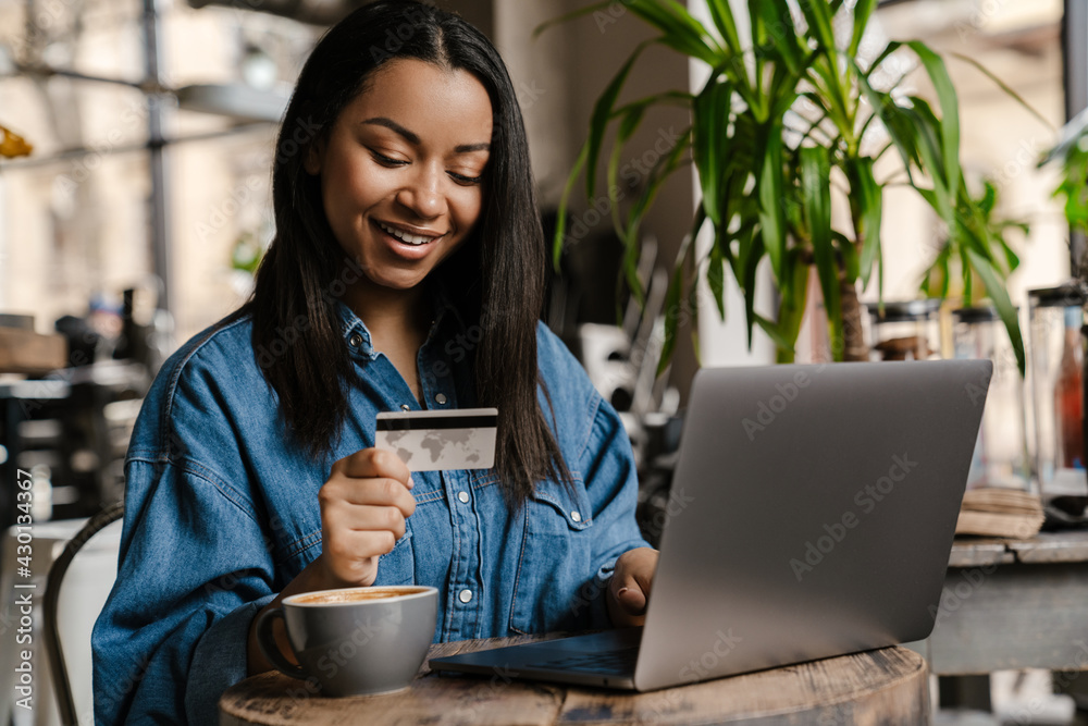 Happy young african woman holding credit card - obrazy, fototapety, plakaty 