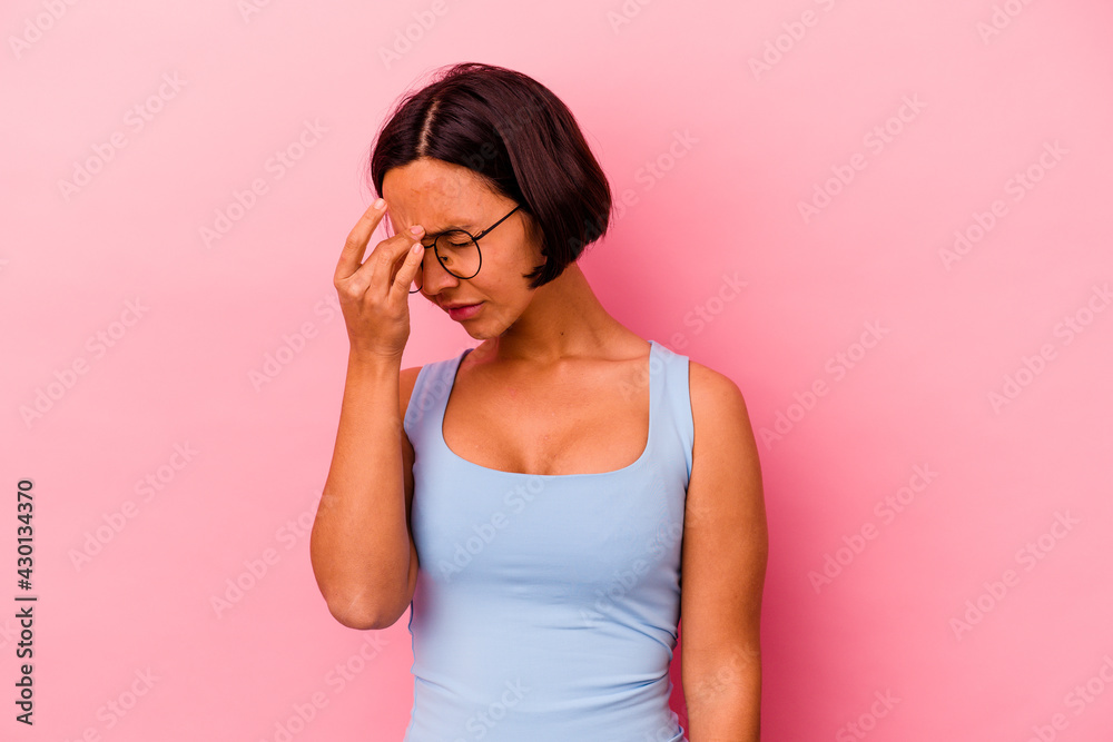 Young mixed race woman isolated on pink background having a head ache, touching front of the face.