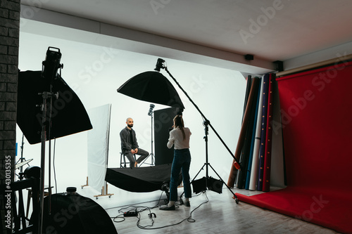 Professional photographer working in the studio with a male model on a white background.