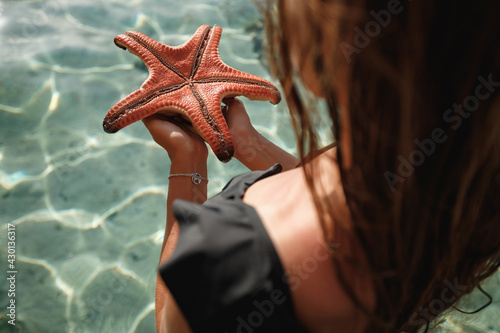 Caucasian girl in the Ccaribbean sea holding a red starfish near face photo