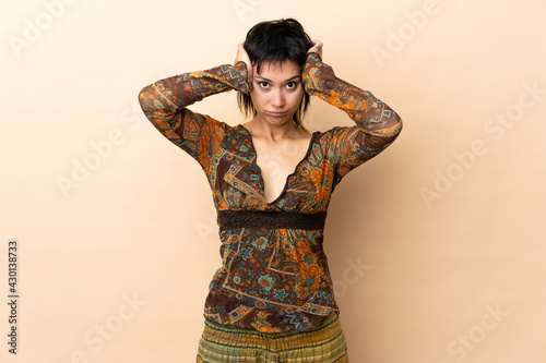 Indian woman isolated on beige background frustrated and covering ears
