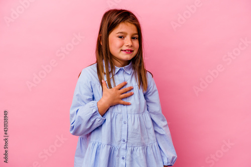 Little caucasian girl isolated on pink background  laughs out loudly keeping hand on chest. © Asier