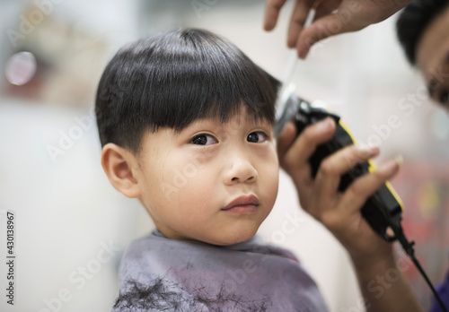 little asian boy having a haircut at barbershop : close up