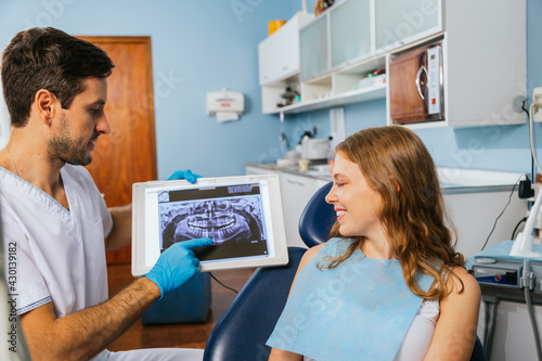 Portrait of an orthodontist dentist showing an X-ray to his patient.