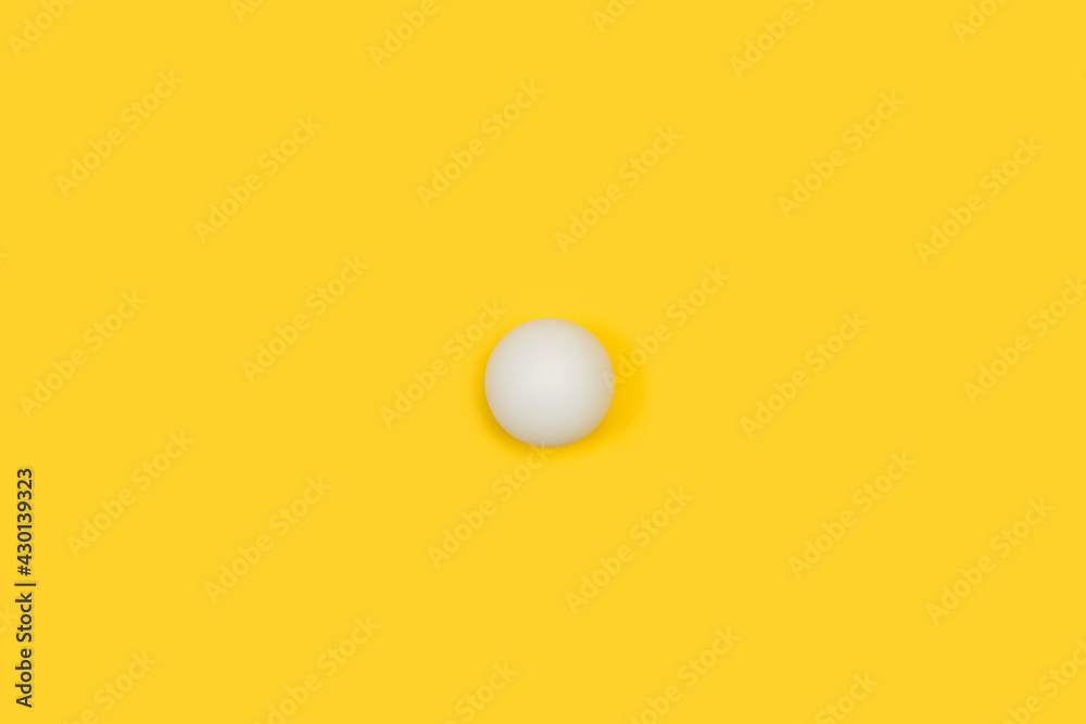 Una pelota blanca de tenis de mesa ping pong sobre un fondo amarillo liso y aislado. Vista superior. Copy space. Concepto: Deportes