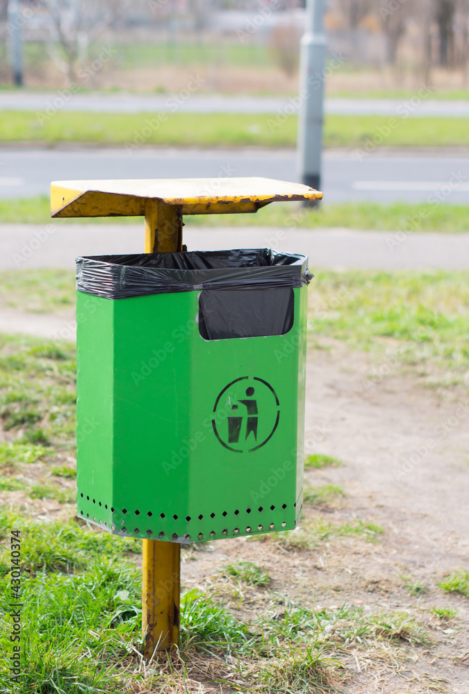POZNA, POLAND - Apr 08, 2015: Green trash bin at a park - obrazy, fototapety, plakaty 