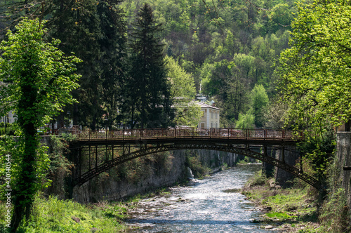 Old wrought iron bridge over a mountain river. A beautiful landscape in the first days of spring.