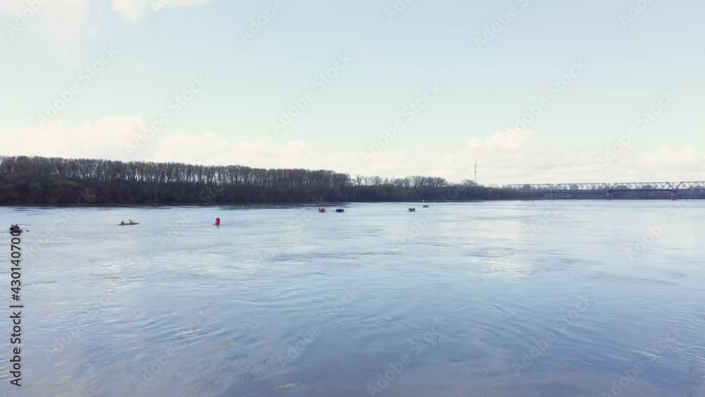 People are sailing on a boat on a gray river that spilled in the spring. Dark forest in the background. Cloudy day, pond. Shooting in motion. High quality. People are sailing on a boat on a gray river that spilled in the spring. Dark forest in the background. Cloudy day, pond. Shooting in motion. High quality.