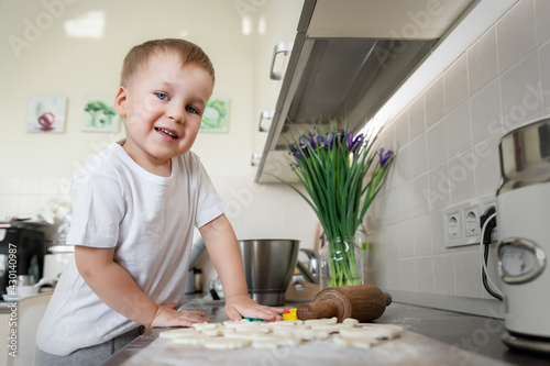 Portrait cute little blond toodler caucasian boy kid cooking sweet tasty cookies gift for mother's day at home kitchen. Mom small son baking sweet pastry homemade dessert. Child fun baking activity