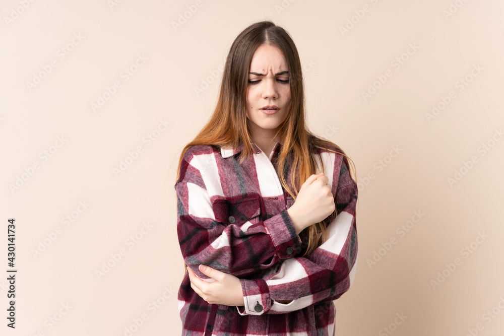 Young caucasian woman isolated on beige background with pain in elbow Young caucasian woman isolated on beige background with pain in elbow
