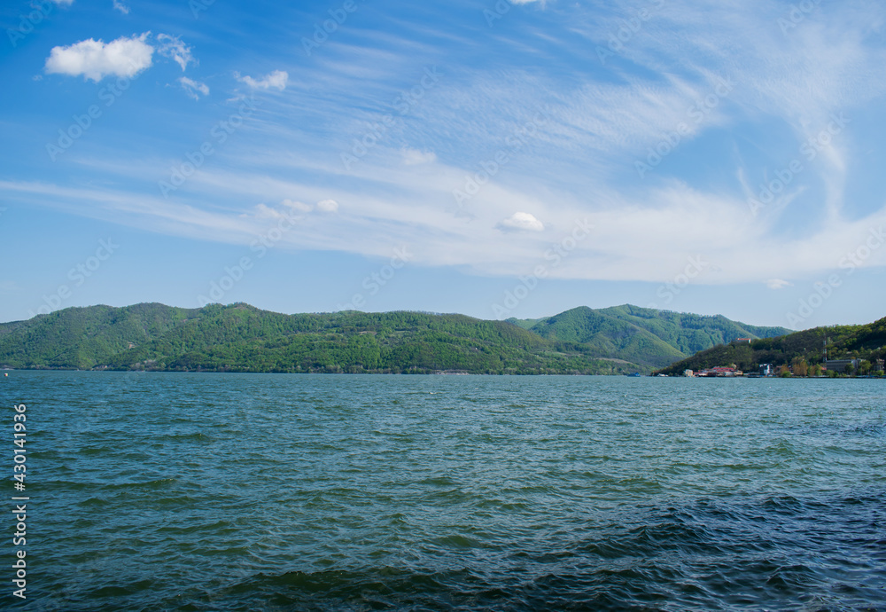 Danube river, with blue water. Mountains covered with vegetation in the distance.