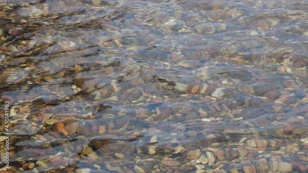 Pure clear water with colored stones on the bottom in the sea or lake Pure clear water with colored stones on the bottom in the sea or lake