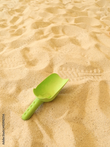 green small shovel on the sand pit with sand on it or empty design for harvest concept