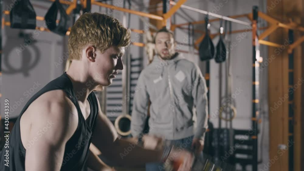 Two people train with battle ropes while trainer cheers them on Two people train with battle ropes while trainer cheers them on