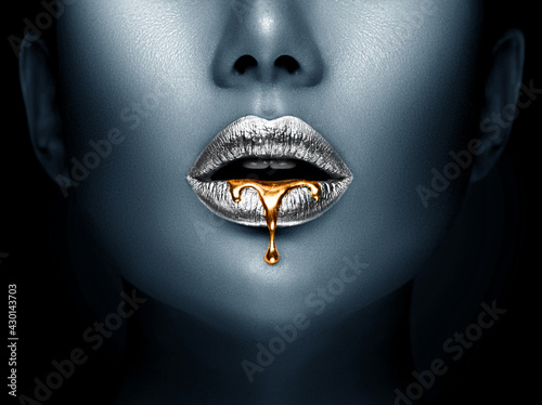 Lipstick dripping. Paint drips, lipgloss dripping from sexy lips, liquid Gold metallic paint drops on beautiful model silver girl's mouth, creative make-up. Beauty woman face makeup close up. Art