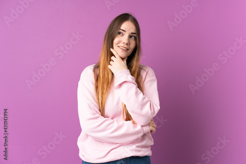 Young caucasian woman isolated on purple background looking up while smiling