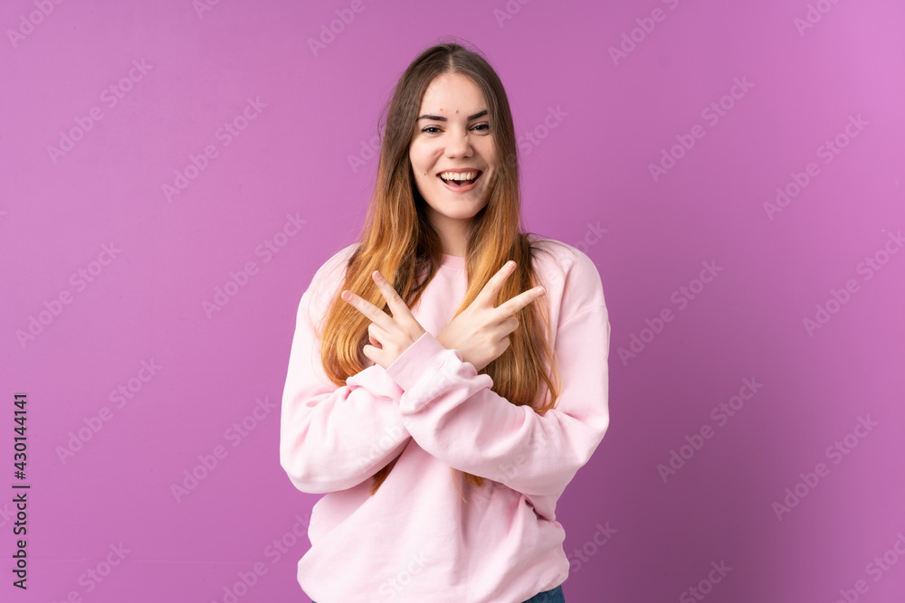 Young caucasian woman isolated on purple background smiling and showing victory sign
