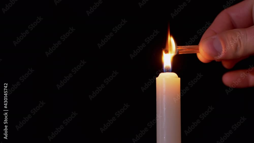 Male Hand Lights Two Matches on a Black Background from a Burning Candle. Bright flame, fire, ignition in a dark room. White candle with yellow fire. Concept of memory, ritual, celebration. 4K Male Hand Lights Two Matches on a Black Background from a Burning Candle. Bright flame, fire, ignition in a dark room. White candle with yellow fire. Concept of memory, ritual, celebration. 4K